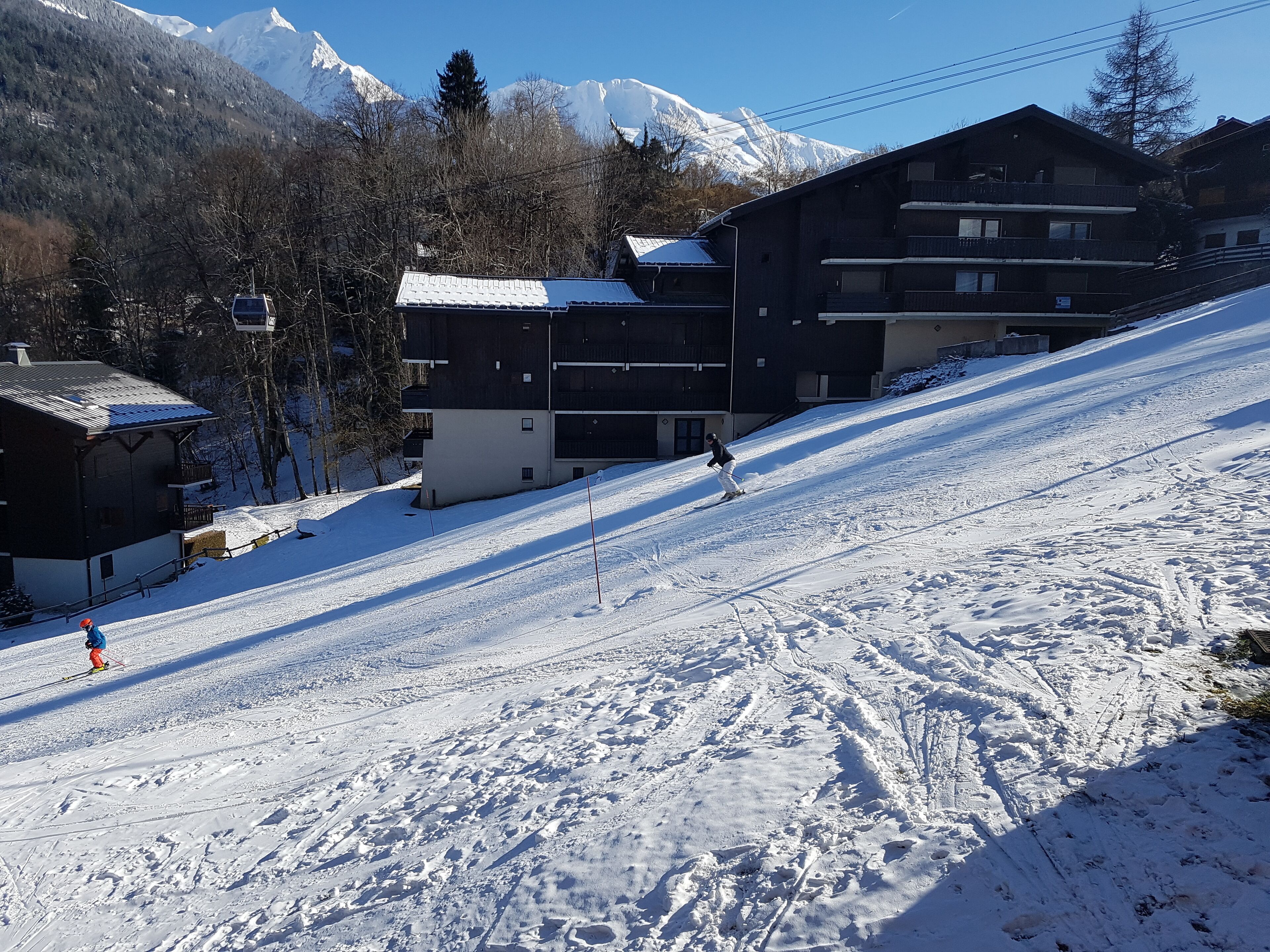 A ski slope with buildings and a mountain in the background.