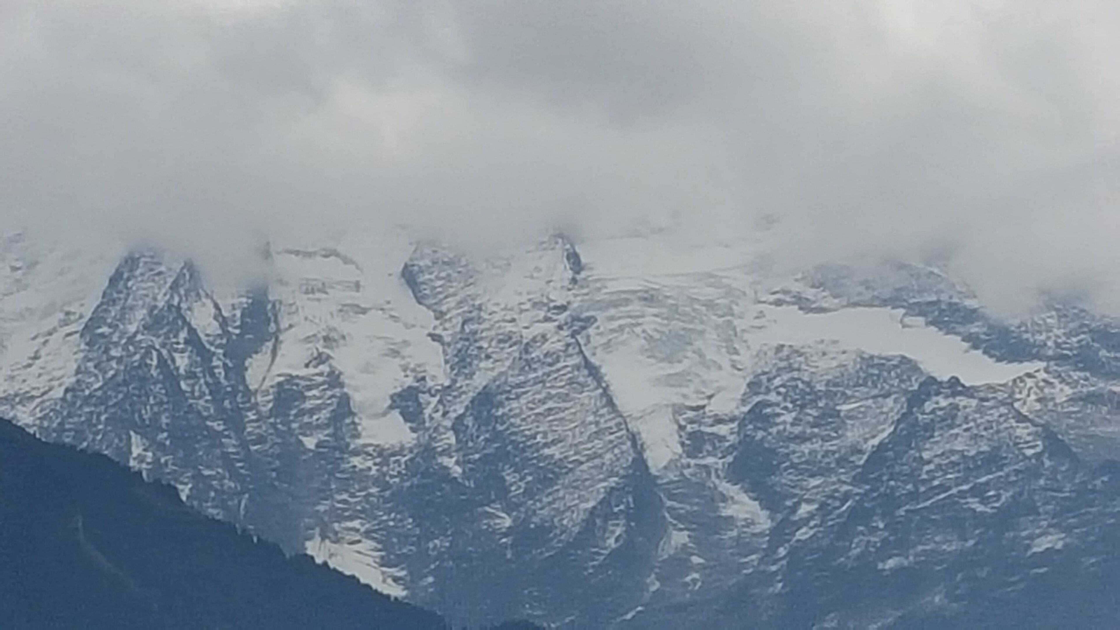 Une chaîne de montagnes aux sommets enneigés, avec une vallée en contrebas.