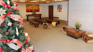 Un vestíbulo amplio con un gran árbol de Navidad, bancos de madera y una mesa de centro de madera.