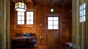 A wooden cabin interior with a table, bench, and two windows. - Beaver Lodge Hakuba (Hakuba)