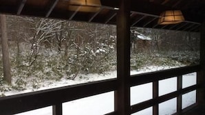 A view through a window with a wooden frame, looking out at a snowy landscape with bare trees. - Beaver Lodge Hakuba (Hakuba)