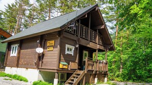 Een houten chalet met balkon, een bord waarop een podium staat aangegeven en een klein terras.