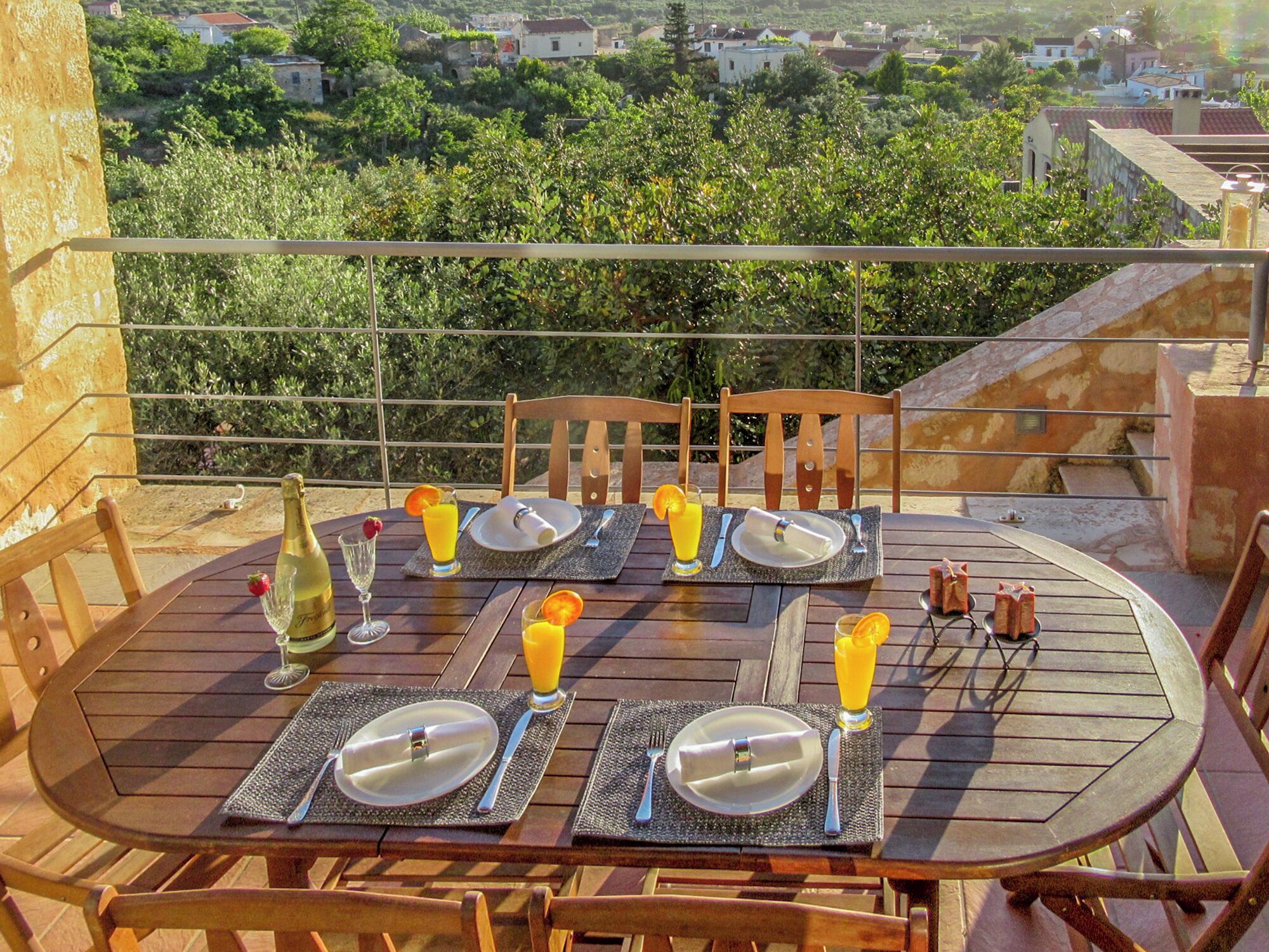 A table set for two with a scenic view, including a bottle of champagne, glasses of orange juice, and a bottle of water.