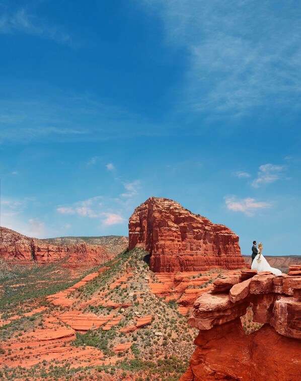 A couple embracing on a red rock formation with a clear blue sky in the background. - Walk a Block to Uptown to the main shops, tours, restaurants. (Sedona)