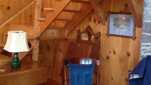 A wooden interior with a rocking chair, a lamp, and a staircase.