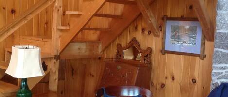 Ein Holzinnenraum mit Schaukelstuhl, Lampe und Treppe.