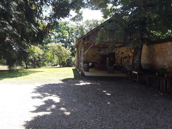 Un edificio rústico con camino de grava, rodeado de árboles y césped.