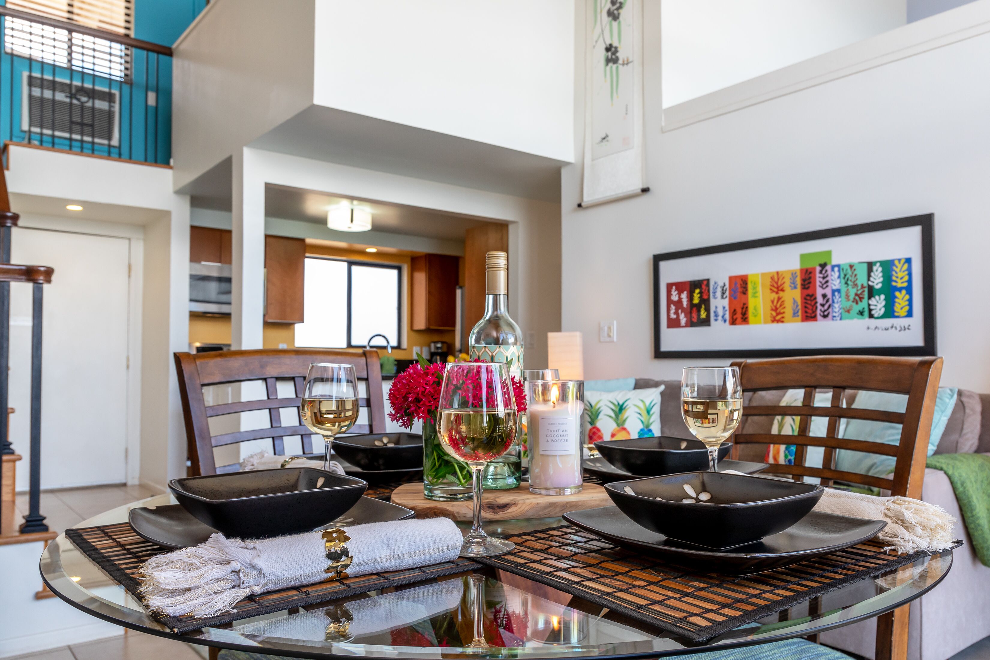 A dining table set with black bowls, wine glasses, and a bottle of wine.
