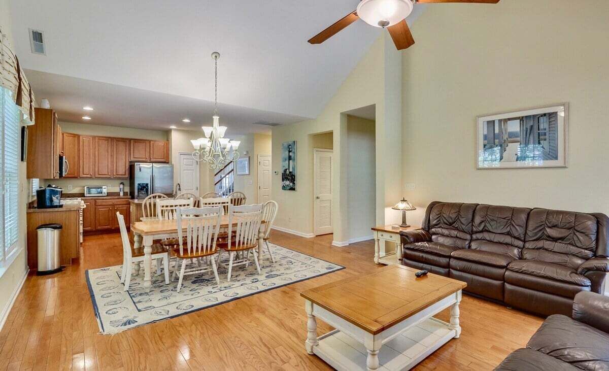 A spacious living room with a dining area, a ceiling fan, and a large window.