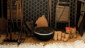 A rustic interior with a woven basket, a large black bowl, and woven footwear. - Yukiwariso (Otari)