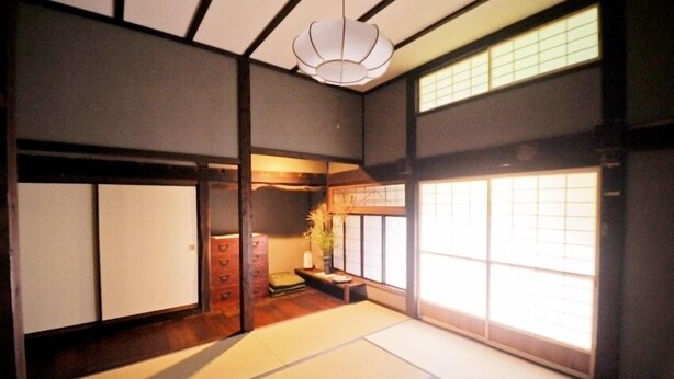 A traditional Japanese room with tatami flooring, sliding doors, and a hanging light fixture. - Yukiwariso (Otari)