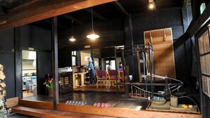 A rustic interior with wooden beams, a seating area, and a display of shoes. - Yukiwariso (Otari)