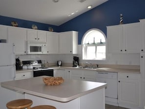 Een moderne keuken met witte kasten, een centraal eiland en een groot raam.