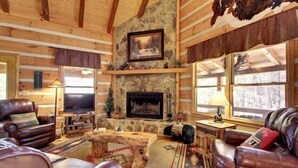 A log cabin interior with a stone fireplace, leather sofas, and a television. - Perfect Getaway Lots 2 Do! Upscale Real-Log Cabin & Great Rate! Families/Couples (Blue Ridge)