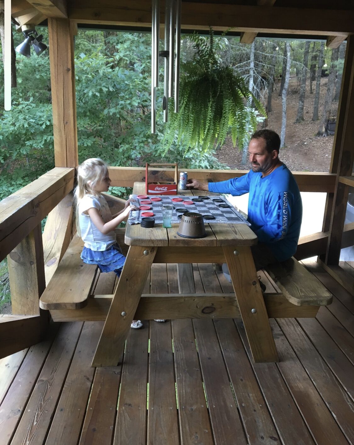 A wooden deck with a picnic table where a man and a child are seated.