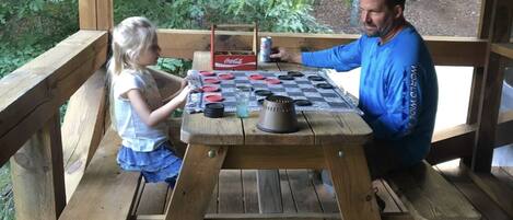 A wooden deck with a picnic table where a man and a child are seated.