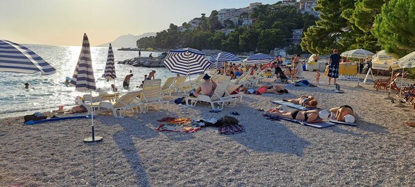Una playa con tumbonas, sombrillas y gente relajándose.