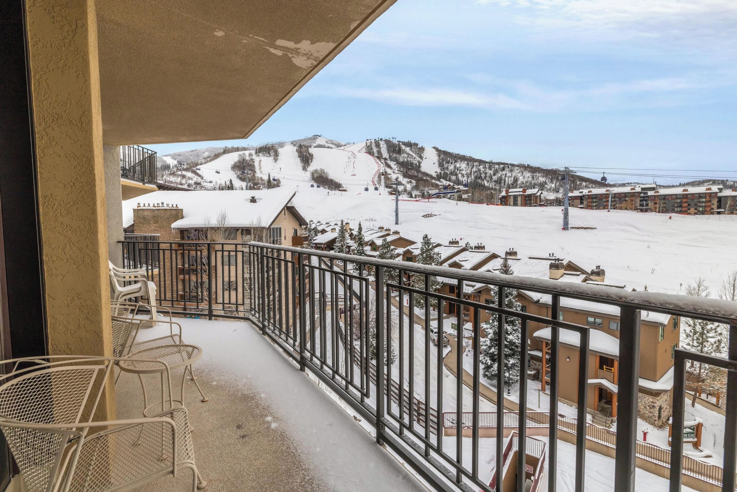 Un balcon avec vue sur une piste de ski enneigée et des bâtiments.