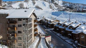 A ski resort with a building featuring balconies and a view of a snowy mountain slope. - Ski-in, Walk-out, Views of Ski Slopes, Indoor Pool, Discount Lift Tix (Steamboat Springs)