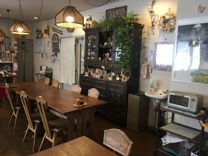 A cozy dining area with a wooden table and chairs, a cabinet with various items, and a hanging plant. - Fujiyoshi (Nozawaonsen)
