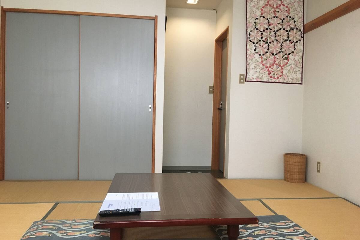 A traditional Japanese room with tatami flooring, a low wooden table, and sliding doors.