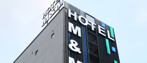 A modern building with a sign that reads "HOTEL M&M".