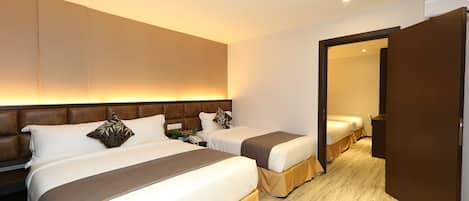 A hotel room with two beds, a wooden headboard, a bedside table with a lamp, and a mirror on the wall.