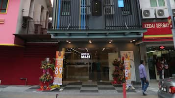 Un hotel con fachada moderna, balcones y un cartel que indica las tarifas de las habitaciones.