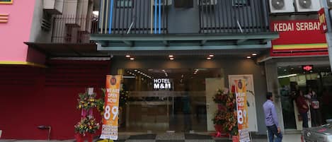 A hotel with a modern facade, balconies, and a sign indicating room rates.