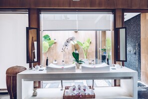 A modern bathroom with two sinks, a large mirror, and a view of a garden through the window.