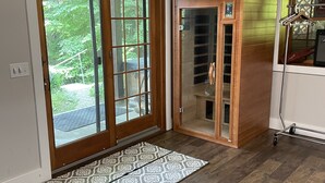 Una habitación amplia con piso de madera, una alfombra estampada y una silla de madera.