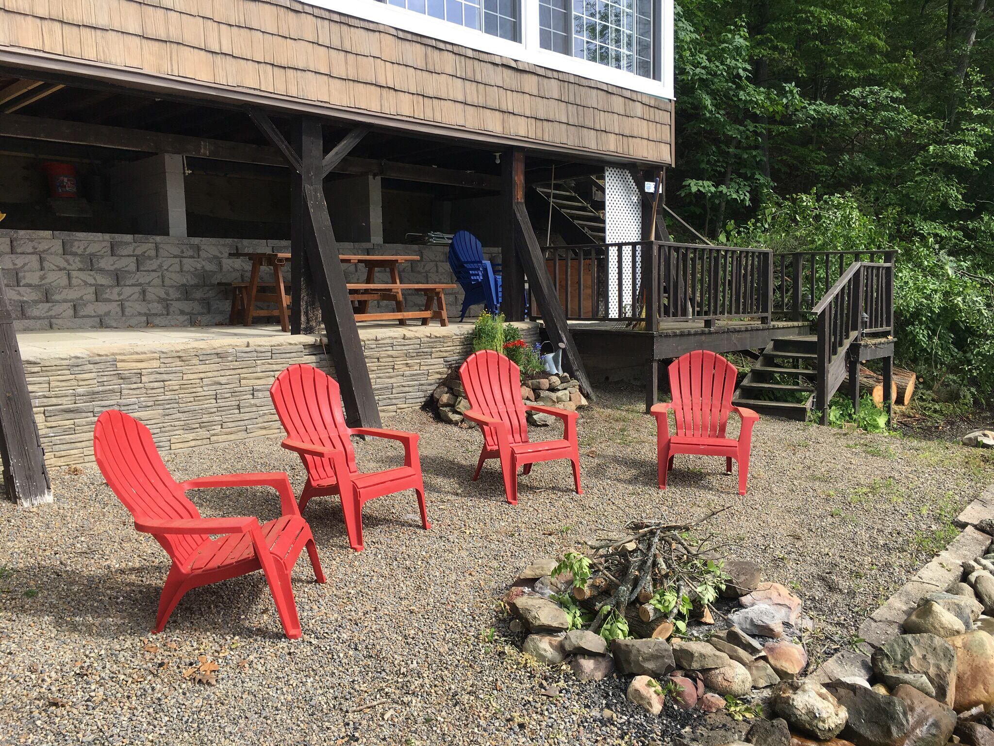 Eine Terrasse mit roten Adirondack-Stühlen, einer Steinmauer und einem Holzdeck mit Treppe.