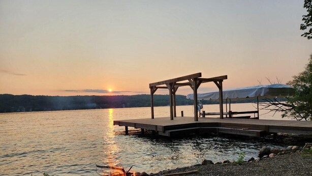 Un entorno junto al lago con un muelle, una fogata y un área de estar cubierta.