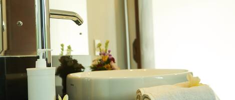 A bathroom sink with a chrome faucet, a white soap dispenser, and a rolled white towel on the counter.