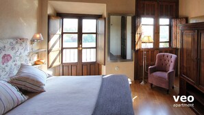 A bedroom with a bed, a chair, a wardrobe, and a mirror.