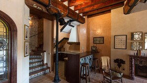 A rustic interior with a wooden staircase, a bar area, and a fireplace.