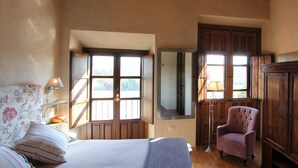 A bedroom with a bed, a chair, a wardrobe, and a mirror.
