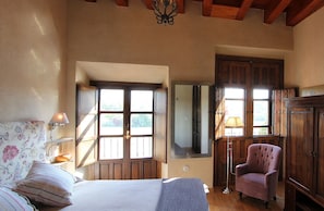 A bedroom with a bed, a chair, a wardrobe, and a mirror.