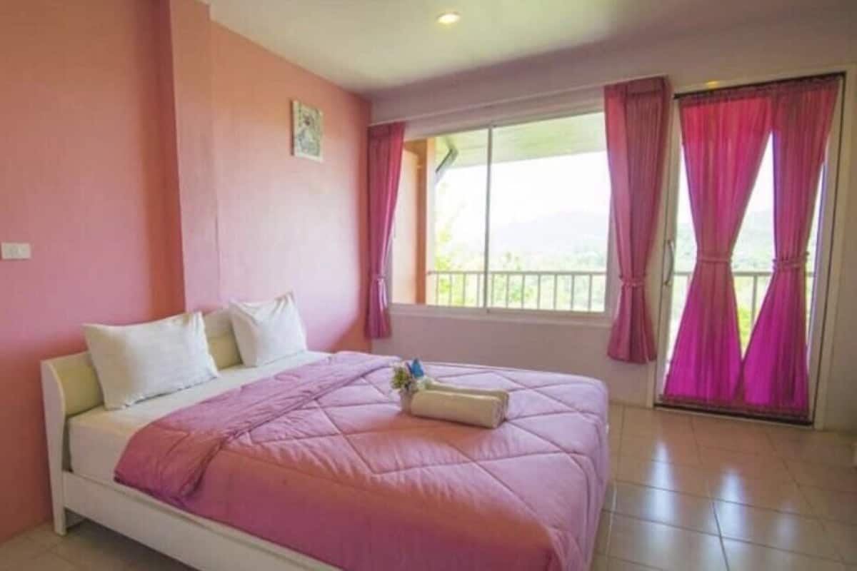 A bedroom with a bed, a window with curtains, and a small balcony.