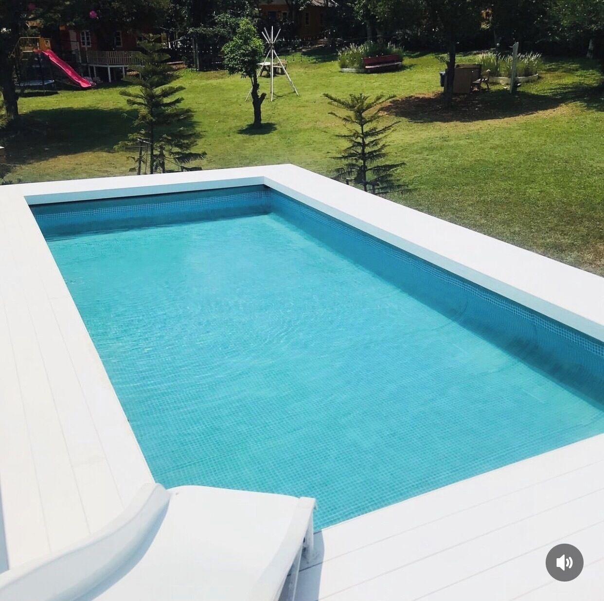 A rectangular swimming pool with a white deck and a clear blue water surface.