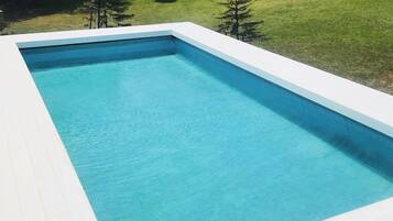 A rectangular swimming pool with a white deck and a clear blue water surface.