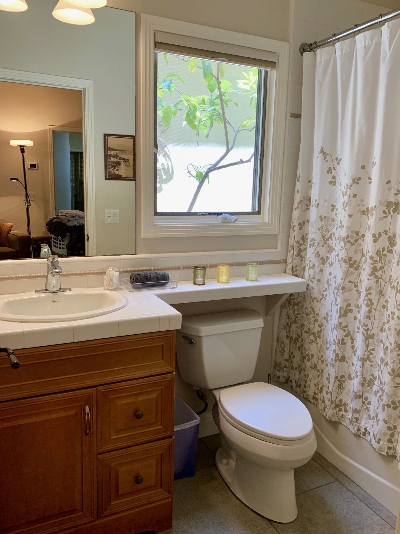 A bathroom with a window, a sink, a toilet, and a shower curtain.