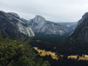 A mountainous landscape with a prominent rock formation in the center, surrounded by dense forests and a valley below. - Quiet, Beautiful, East Sacramento Oasis - Walk to Coffee, Restaurants and Shops (SACRAMENTO)