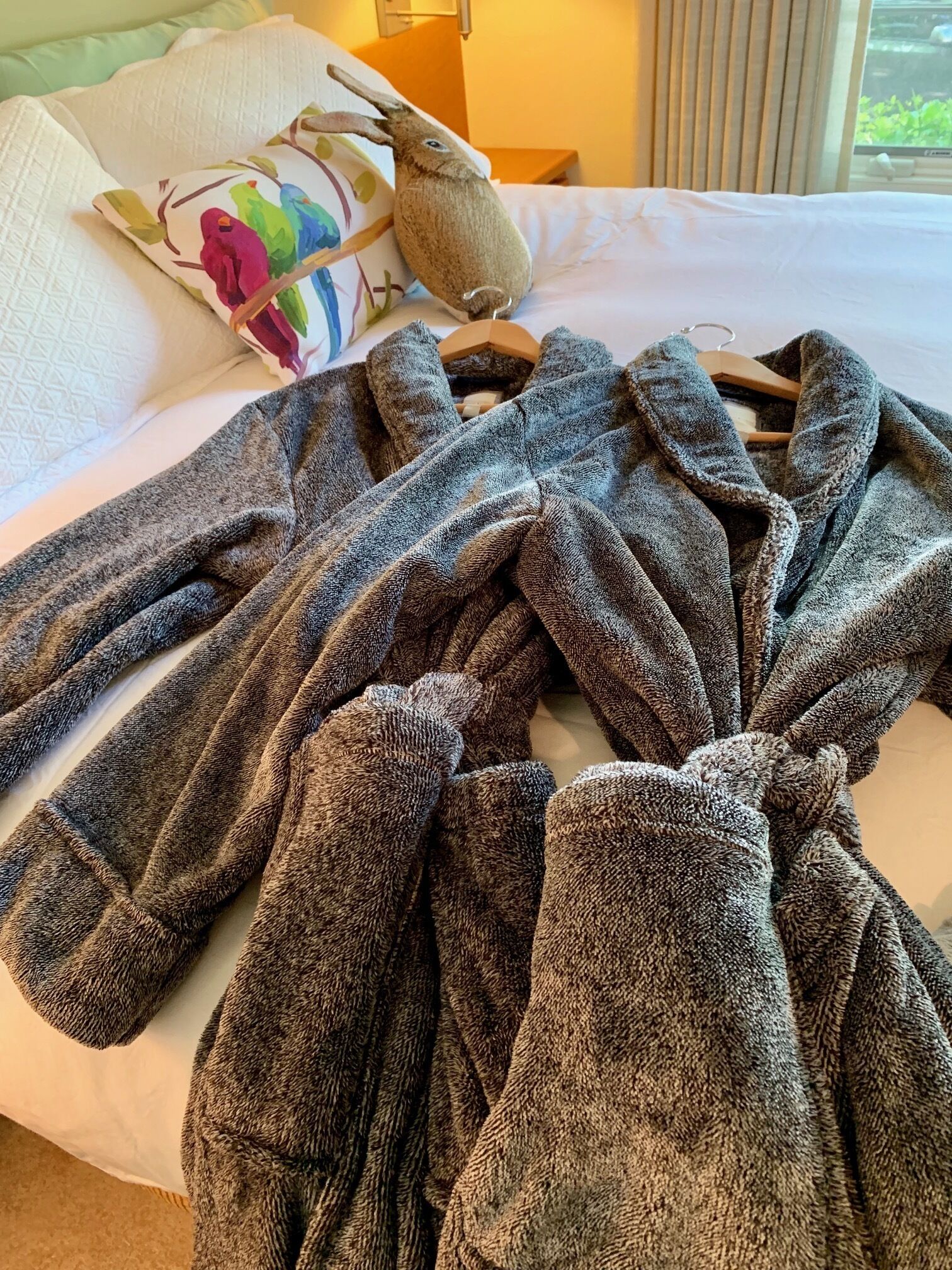 A bed with a large, grey, textured blanket spread out.