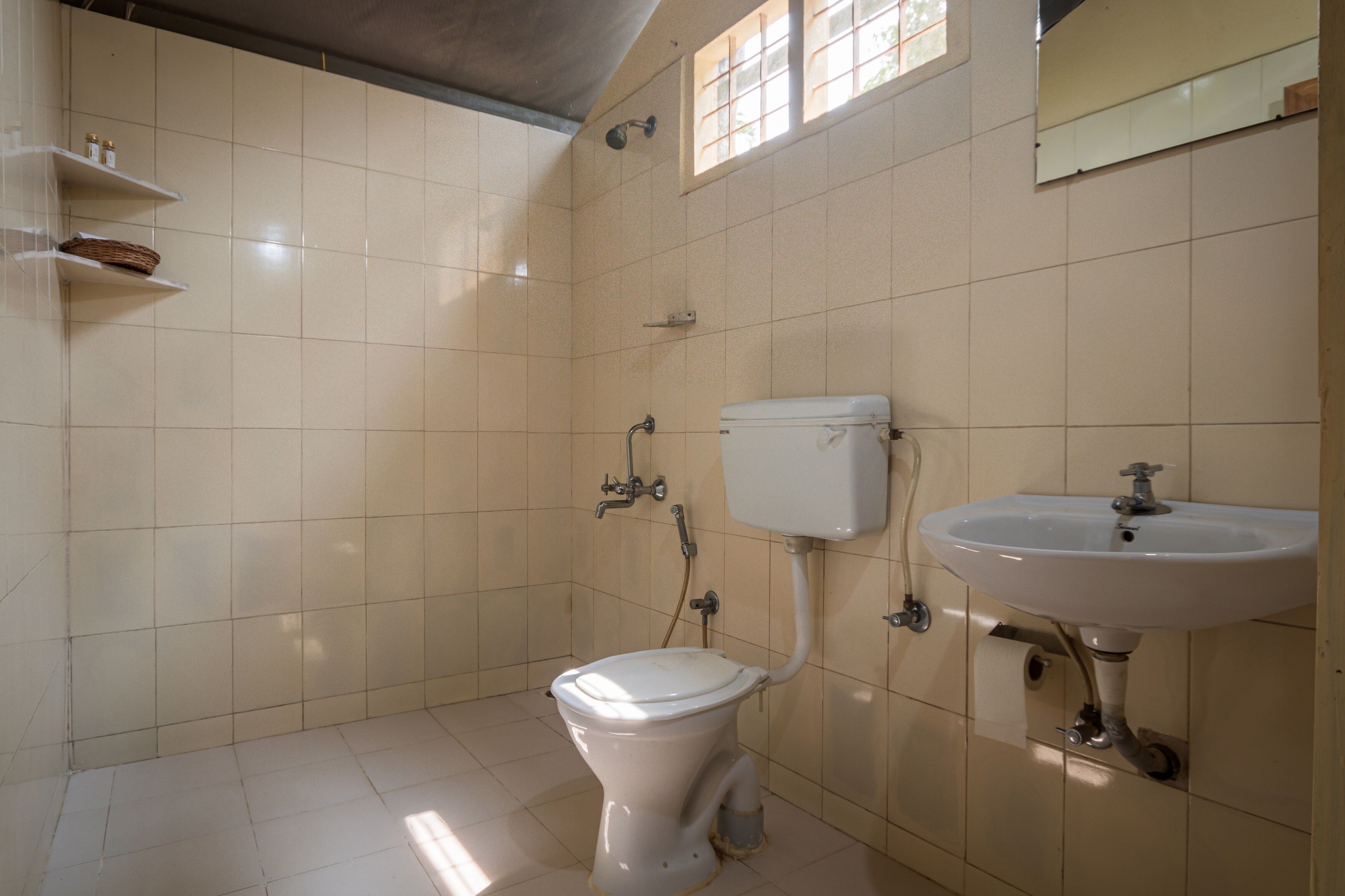 A bathroom with a toilet, sink, and shelves with toiletries.