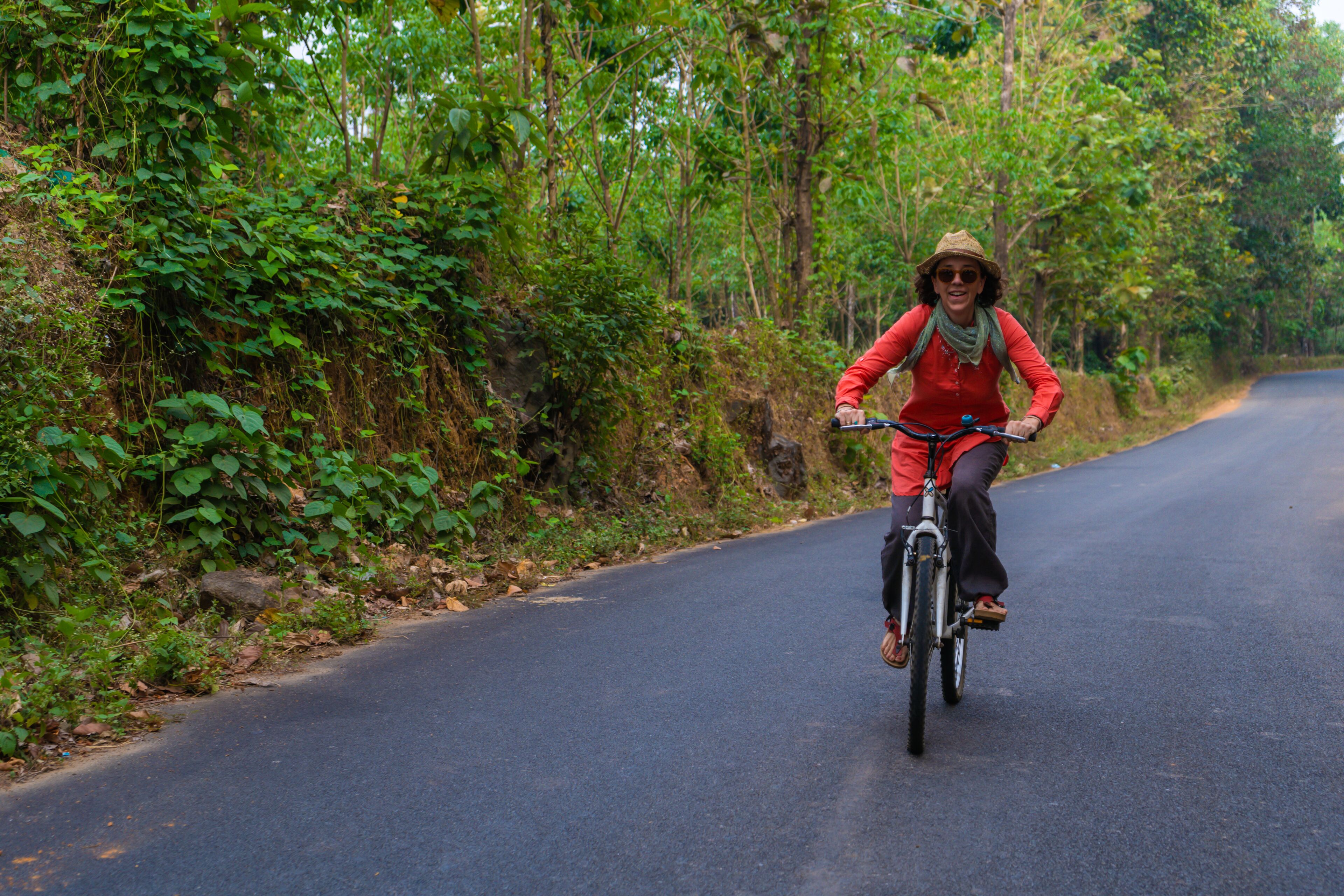 A person riding a bicycle on a road surrounded by dense greenery.