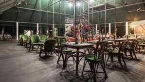A spacious indoor area with high ceilings, green chairs, tables, and ceiling fans. - Amritara Riverside Camp, Thattekad (Kothamangalam)