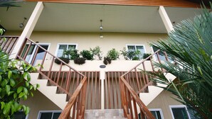 Una escalera que lleva a un edificio con barandilla de madera, paredes color beige y ventanas.