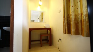 Un baño pequeño con una mesita de madera, un espejo y una pila de toallas.