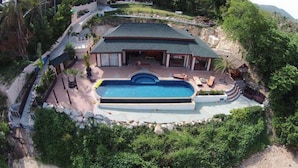 A large house with a swimming pool, surrounded by lush greenery and a hilly landscape. - 5 Bedroom Sea Front Villa SDV231 - Koh Phangan-By Samui Dream Villas (Ko Pha-ngan)